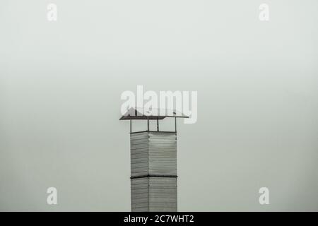 Old metal chimney on the roof on foggy day Stock Photo
