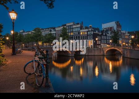 The lonely bike beside the canals at night in the illuminated Amsterdam, the Netherlands Stock Photo