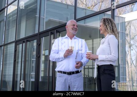 Colleagues having a nice discussion during the coffee break outside the office building Stock Photo
