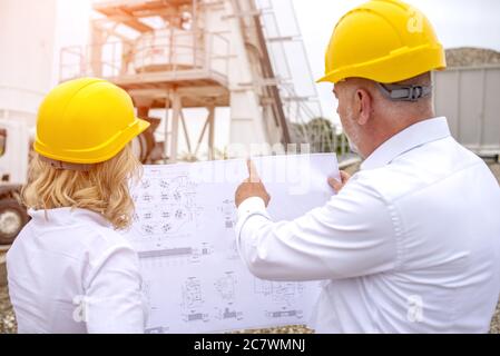 Engineers on site wearing safety helmets and discussing the project details Stock Photo