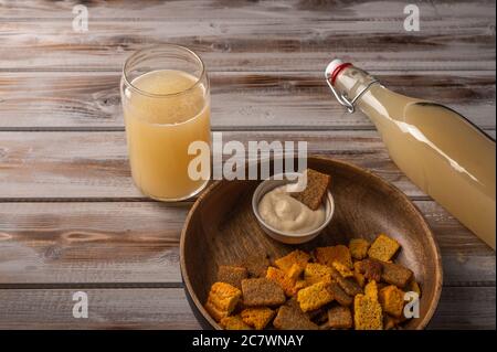 Top view homemade tradishional russian light rye kvass in bottle with glass cup and crackers on wooden background. Wonderful healthy refreshing drink for summer Stock Photo