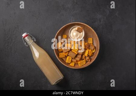 Top view homemade tradishional russian light rye kvass in bottle and crackers on dark wooden background. Wonderful healthy refreshing drink for summer Stock Photo
