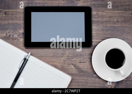 Empty digital tablet pc with notebook and coffee on a wood table Stock Photo