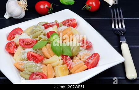 Pasta with cherry tomatoes, parmesan and basil on black wooden table Stock Photo