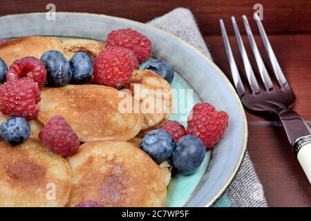 Mini pancakes with raspberries and cranberries on table Stock Photo