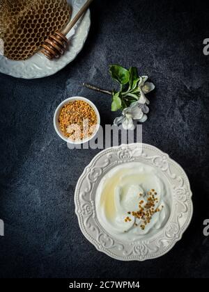 Yoghurt with bee pollen grains and honey in white ceramic bowl. Stock Photo