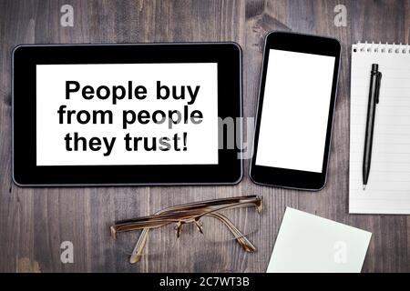 People buy from people they trust! Text on tablet device on a wooden table Stock Photo