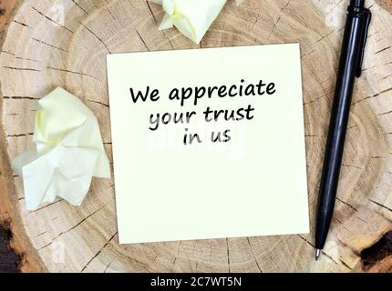 We appreciate your trust in us. Text on paper on a wooden table Stock Photo