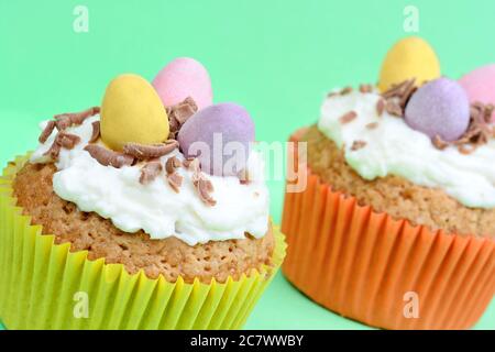 Close up of cupcakes with chocolate eggs on green background Stock Photo