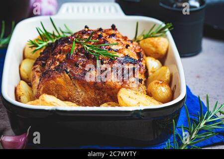 Roast pork with potatoes in an oven dish, black background. Stock Photo