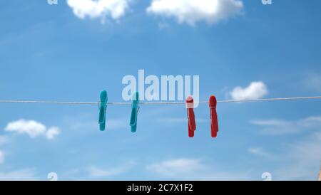clothespins on a rope against the background of a bright blue sky with clouds Stock Photo