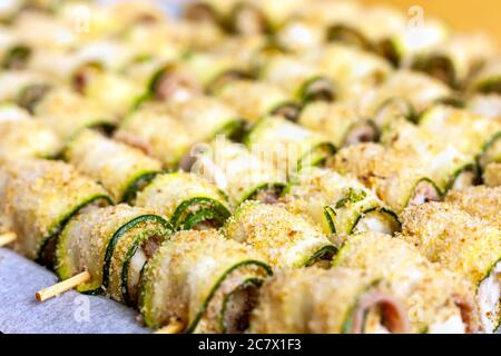Skewers of courgette rolls prepared to be baked or grilled. Street food concept. Summertime healthy eating. Selective focus. Stock Photo