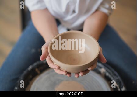 Cuts of product with wire. Craftsman hands making pottery bowl. Woman working on potter wheel. Family business shop sculpts pot from clay. Stock Photo