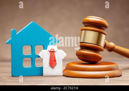 House with businessman in shirt and tie and judge gavel on brown background. Concept of selling a home by auction or sentence by right. Stock Photo