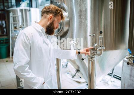 Professional caucasian technologist expert controlling industrial process in production plant. Industrial worker with uniform checking productivity Stock Photo