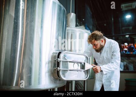 Professional caucasian technologist expert controlling industrial process in production plant. Industrial worker with uniform checking productivity Stock Photo