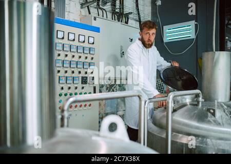 Professional caucasian technologist expert controlling industrial process in production plant. Industrial worker with uniform checking productivity Stock Photo