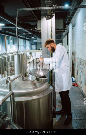 Professional caucasian technologist expert controlling industrial process in production plant. Industrial worker with uniform checking productivity Stock Photo