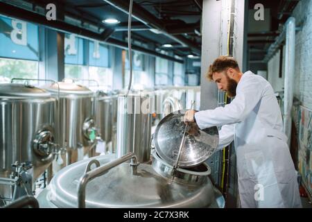 Professional caucasian technologist expert controlling industrial process in production plant. Industrial worker with uniform checking productivity Stock Photo