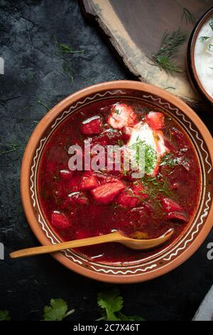 Vegetarian borstch served in traditional clay bowl on dark background Stock Photo