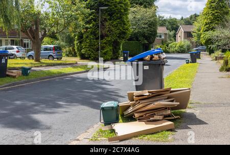 Roadside recycling wheelie bins and overflowing cardboard packaging awaiting refuse collection in a suburban street in Woking, Surrey, SE England Stock Photo