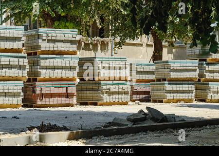 Pallets with paving slabs prepared for laying at a city road construction site on a sunny summer day. Repair of roads and sidewalks. Improvement. Stock Photo