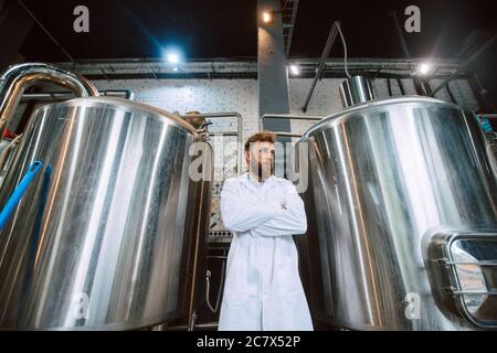 Portrait of professional caucasian handsome technologist expert in white uniform standing in pharmaceutical or food factory  - production plant Stock Photo