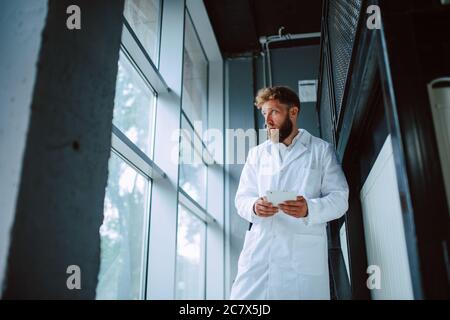 Professional caucasian technologist expert  in white uniform stands on steps in production plant - factory Stock Photo