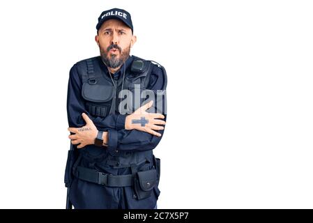 Young handsome man wearing police uniform shaking and freezing for winter cold with sad and shock expression on face Stock Photo