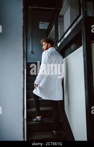 Professional caucasian technologist expert  in white uniform stands on steps in production plant - factory Stock Photo