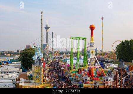 Aerial top sunny view of amusement park, carnival  or festival called Rheinkirmes, with crowd of visitors and colourful illuminating of amusement ride Stock Photo