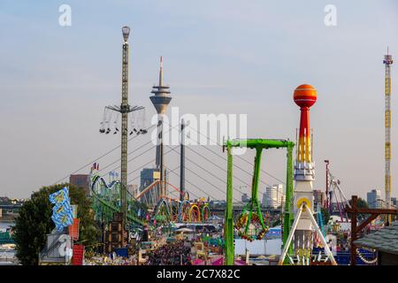 Aerial top sunny view of amusement park, carnival  or festival called Rheinkirmes, with crowd of visitors and colourful illuminating of amusement ride Stock Photo