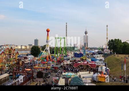 Aerial top sunny view of amusement park, carnival  or festival called Rheinkirmes, with crowd of visitors and colourful illuminating of amusement ride Stock Photo