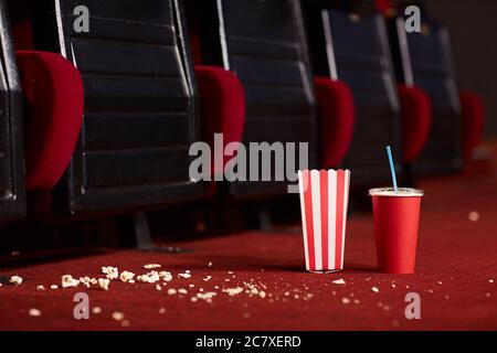 Close up background image of soda cup and popcorn on messy red floor in empty cinema theater, copy space Stock Photo