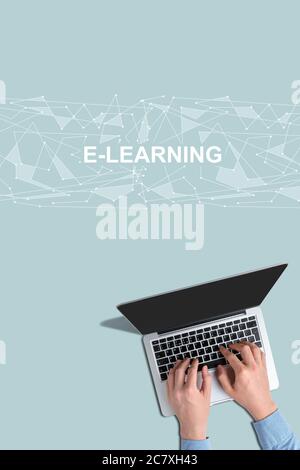 Hands with laptop with top view on a turquoise background with the inscription e-learning. Stock Photo
