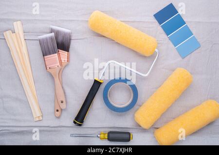 Photograph of professional grade paintbrushed and paint roller frame with extra rollers, paint stirring sticks, screwdriver, masking tape and paint sa Stock Photo