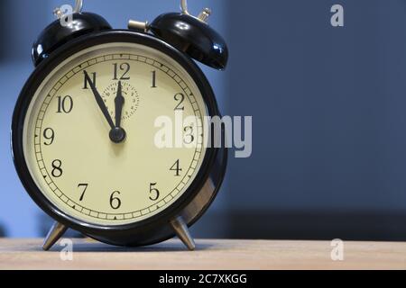 Retro black and metallic  analogue alarm  on a blue background Stock Photo
