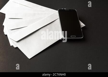 black office desk table with smartphone with blank screen on top of mail envelopes top view business concept Stock Photo