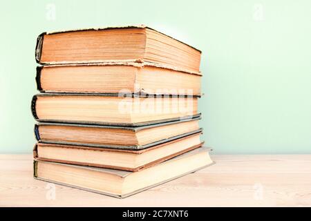 Stack of old used books on wooden table and blue background. Pile of vintage old hardback books. Back to school. Stock Photo