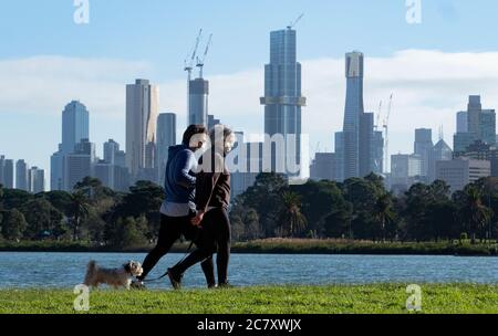 Coronavirus Melbourne Covid-19. People wearing protective face masks walk in Melbourne with the city skyline in the background. Stock Photo