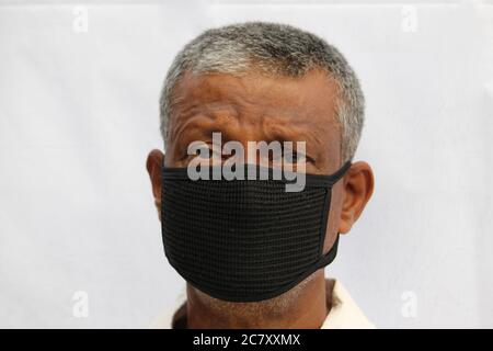 Black protection mask wearing sad or worried senior Indian man portrait on white background. Stock Photo