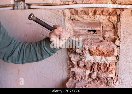 Worker breaking the wall with hammer and chisel in a construction site Stock Photo