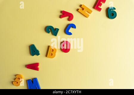 Multi-colored English letters and numbers on yellow background. Kid's set for teaching reading and counting. Concept of education, back to school. Top Stock Photo