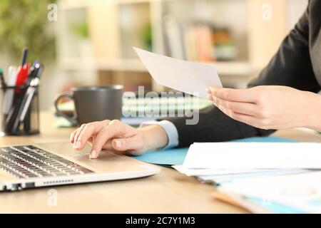 Close up of entrepreneur woman hands working on laptop holding receipt at home office Stock Photo