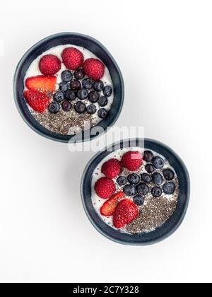 Two blue bowls with yoghurt and fruits isolated on white background. Stock Photo