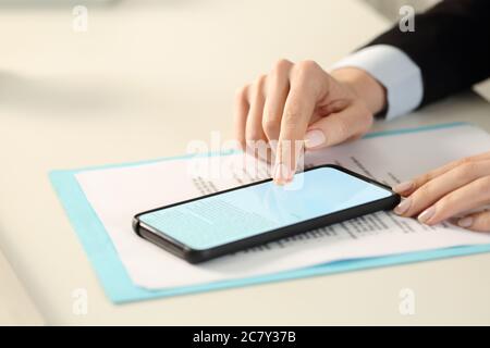 Close up of executive hands signing digital contract on phone screen with finger sitting on a desk at the office Stock Photo