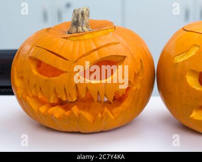 Halloween big orange pumpkin decorated with scary face. Jack O' Lantern on white table background Stock Photo