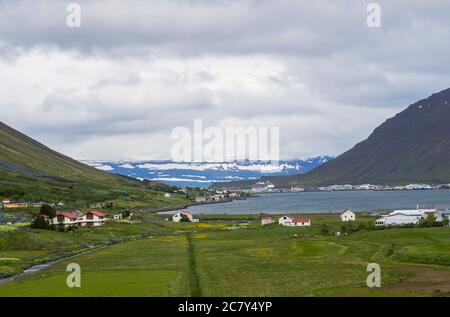 Beautiful view on Isafjordur city, capital of west fjords of Iceland in summer with red houses, harbor with ships and yachts, green grass and farm Stock Photo