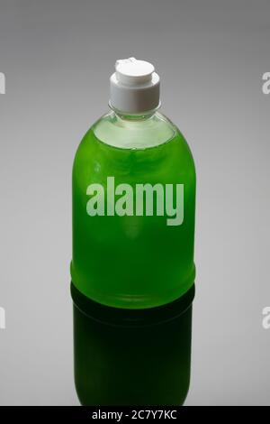 Soap bottle on grey background with shadow. Green color dishwashing liquid. Stock Photo