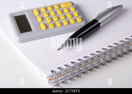 close up of note book with checked pages, pen and calculator Stock Photo